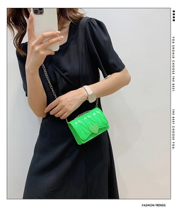Detail of neon green mini crossbody bag with heart buckle and gold chain strap