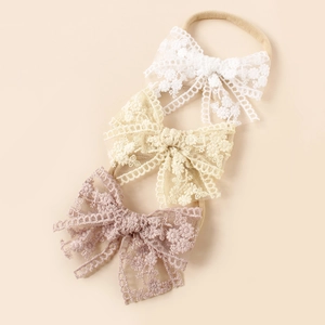 Detailed view of three lace floral embroidery baby headbands in neutral and pink tones