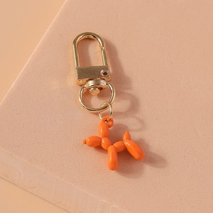 Detail of creative orange balloon dog keychain with golden lobster clasp on pink stand