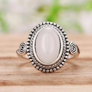 Detail eines Vintage-Boho-Silberrings mit ovalem Mondstein auf hellem Holzgrund