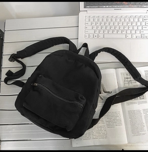 Mini schwarzer Canvas Rucksack mit Reißverschlusstasche auf Metalltisch mit Laptop