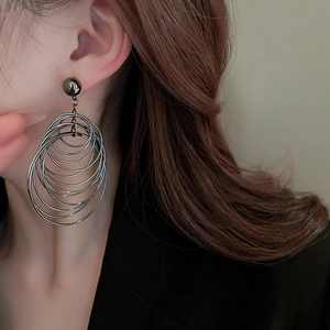 Close-up of model wearing gunmetal multi-layered hoop earrings with a metallic finish