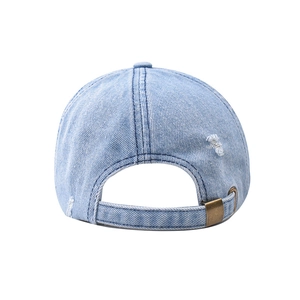Dettaglio del cappellino da baseball in denim lavato con fori usurati e fibbia in metallo
