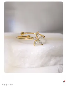 Dettaglio macro di anello a fiore placcato oro 18k con petali di zircone su pietra bianca