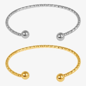 Detail of gold and silver open bangles with textured ripple finish and polished beads