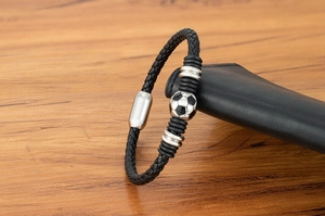 Detail of a braided leather soccer bracelet with a silver magnetic clasp on wood