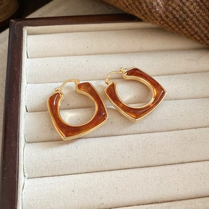 Detail of 18k gold plated amber resin square earrings in a beige velvet jewelry box