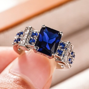 Detailed macro view of a rectangle-cut blue gemstone ring with micro-pave silver band