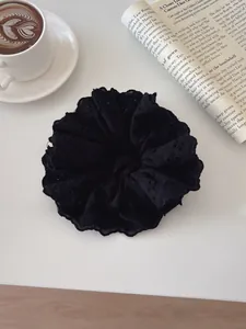Close-up of black floral lace scrunchie with intricate embroidery on minimalist desk