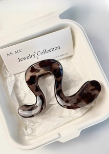 Detailed view of brown tortoiseshell acetate hair claw clip in a white gift box packaging