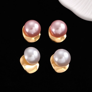 Detail of pink and white large pearl C-shape earrings on black velvet background