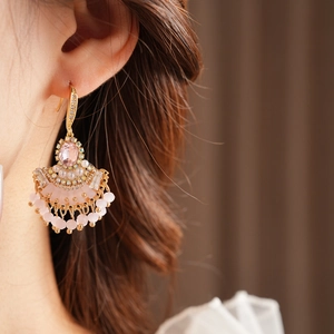 Détail d'une boucle d'oreille éventail avec zircons roses et pompons de perles