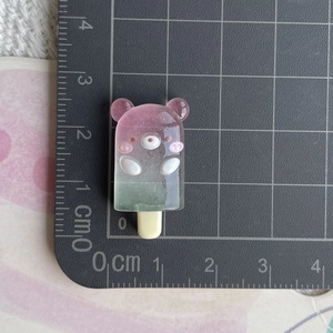 Détail d'une breloque ours en résine dégradé rose avec règle de mesure de la taille