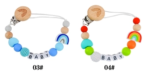 Detail of wooden pacifier clips with silicone rainbow beads and crochet yarn balls