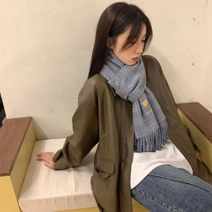 Blue plaid scarf with heart embroidery and tassels worn by a model in a natural setting