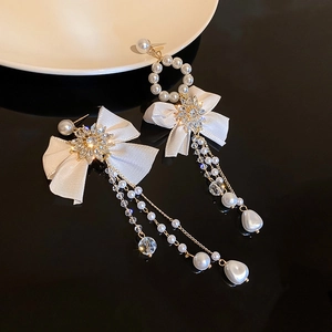 Detail of silk bow earrings with crystal cluster and asymmetric pearl tassel on a black base