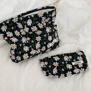 Detail of two-piece daisy embroidery bag set on white linen showing fine floral texture