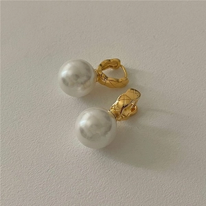 Elegant gold drop earrings with white pearls and quilted texture on refined cream background