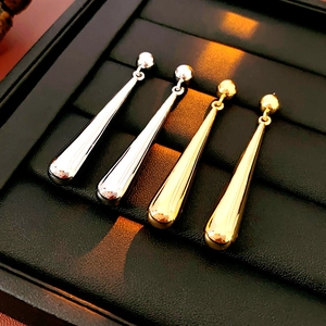 Detailed view of drop-shaped earrings in gold and silver finish on a black display