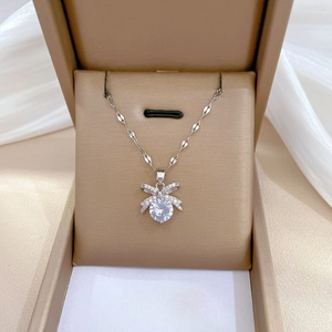 Close-up of silver bow pendant with crystal center in a luxury brown jewelry gift box