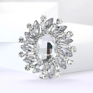 Macro detail of silver starburst brooch with oval glass stone and clear zircon accents