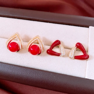 Détail de boucles d'oreilles triangle en plaqué or 18k avec résine rouge et zircone