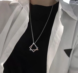 Macro detail of geometric interlocking triangle pendant necklace on a silver chain
