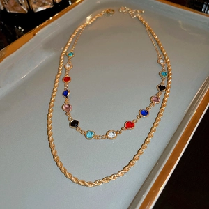 Detail of layered gold rope chain and multi-colored zircon gemstone pendant necklace