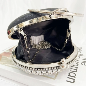 Detail of black rhinestone evening bag with silver metal chain and round sparkling frame