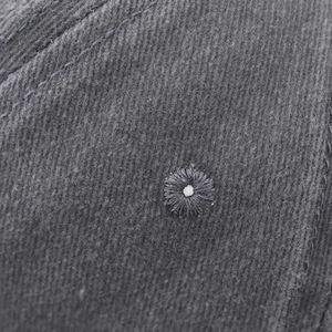 Macro detail of charcoal grey washed cotton twill fabric with embroidered ventilation eyelet