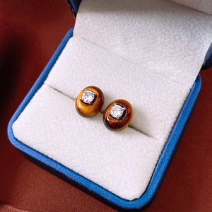 Macro shot of oval tiger eye stud earrings with cubic zirconia in a jewelry box