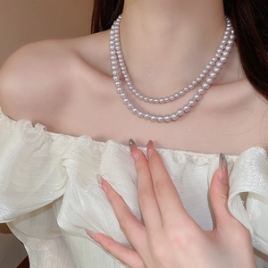 Detailed close-up of double-layer lavender pearl necklace on model neck with elegant ruffles