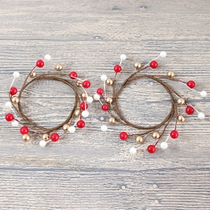 Set of two Christmas candle rings with red and gold berries on brown rattan wreath