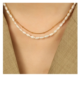 Detail of elegant double-layer necklace with freshwater pearls and gold beads on a model
