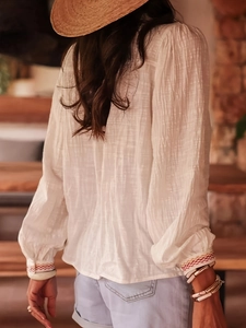 Boho witte blouse met geborduurde lantaarnmouwen, gestyled met een strohoed en etnische sieraden