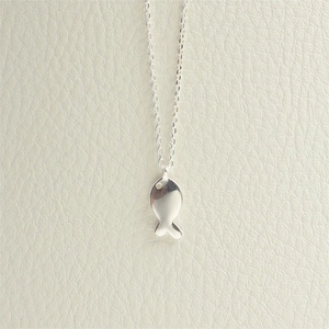 Close-up of minimalist silver fish pendant necklace against a beige leather background
