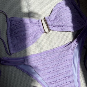 Close-up of lavender ruched bikini with central gold U-shaped metal hardware detail