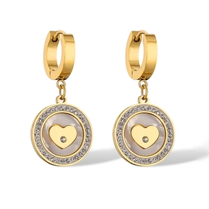 Macro detail of gold earrings featuring zircon, mother of pearl inlay, and heart motif