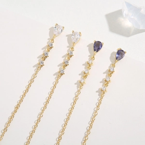 Detail of gold drop earrings with clear and purple crystals on ice decorative blocks