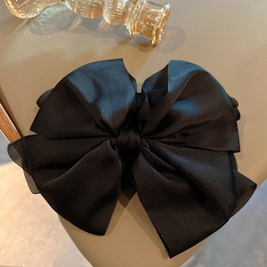 Détail de la pince à cheveux avec nœud en satin noir montrant la texture soyeuse