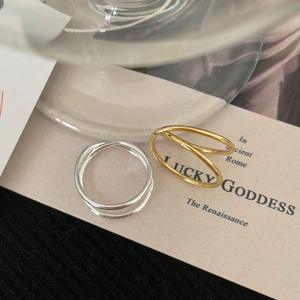 Close-up of minimalist S925 sterling silver and gold layered rings with interlaced lines