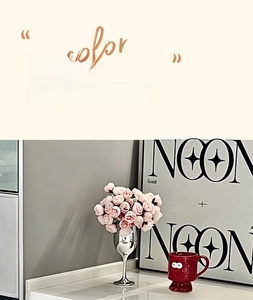 Detail view of pink artificial flowers in a silver vase next to a red ceramic mug