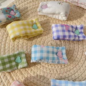 Detailed view of colorful plaid and floral heart-shaped fabric cable organizers on straw mat