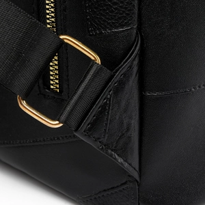 Close-up of black pebble leather backpack with gold hardware and nylon straps