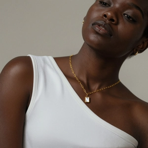 Gros plan du collier à pendentif rectangulaire doré avec nacre et boucles d'oreilles créoles