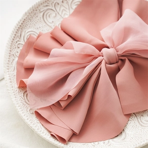 Close-up of elegant pink fabric bow hair clip with soft texture on decorative ceramic plate
