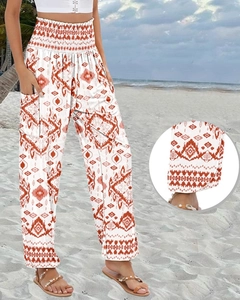 Detail of high-waist boho floral wide-leg trousers with side pockets on a beach