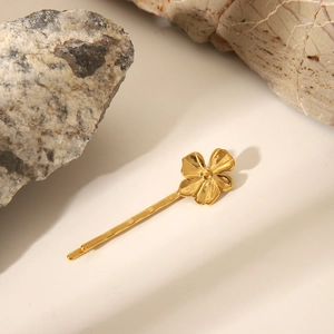 Dettaglio di un fermaglio per capelli a fiore dorato su pietra naturale e luce morbida