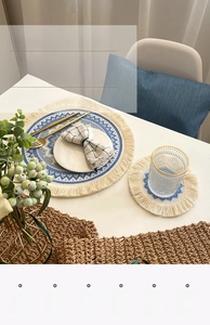 Close-up of cotton linen round placemat with blue ethnic weave and cream fringe