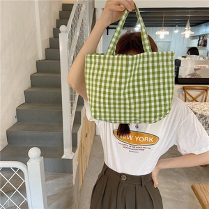 Green checkered cotton linen lunch bag shown by model in a cozy cafe setting